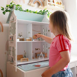 Child engaging with the Barnshenn wooden doll house, showcasing its charming interior design and educational play features