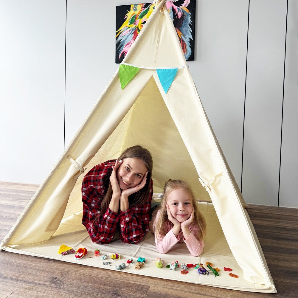 Mother and daughter smiling inside a play tent decorated with colourful bunting, lying on the floor surrounded by small toys.